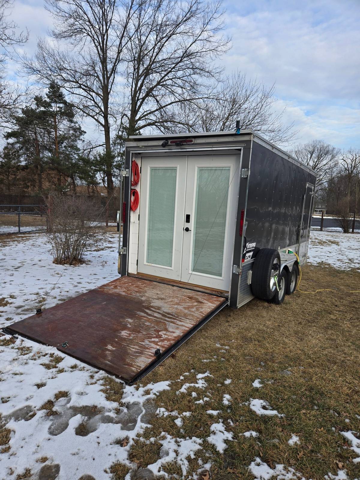 Black cargo trailer conversion with French doors and its original rear ramp