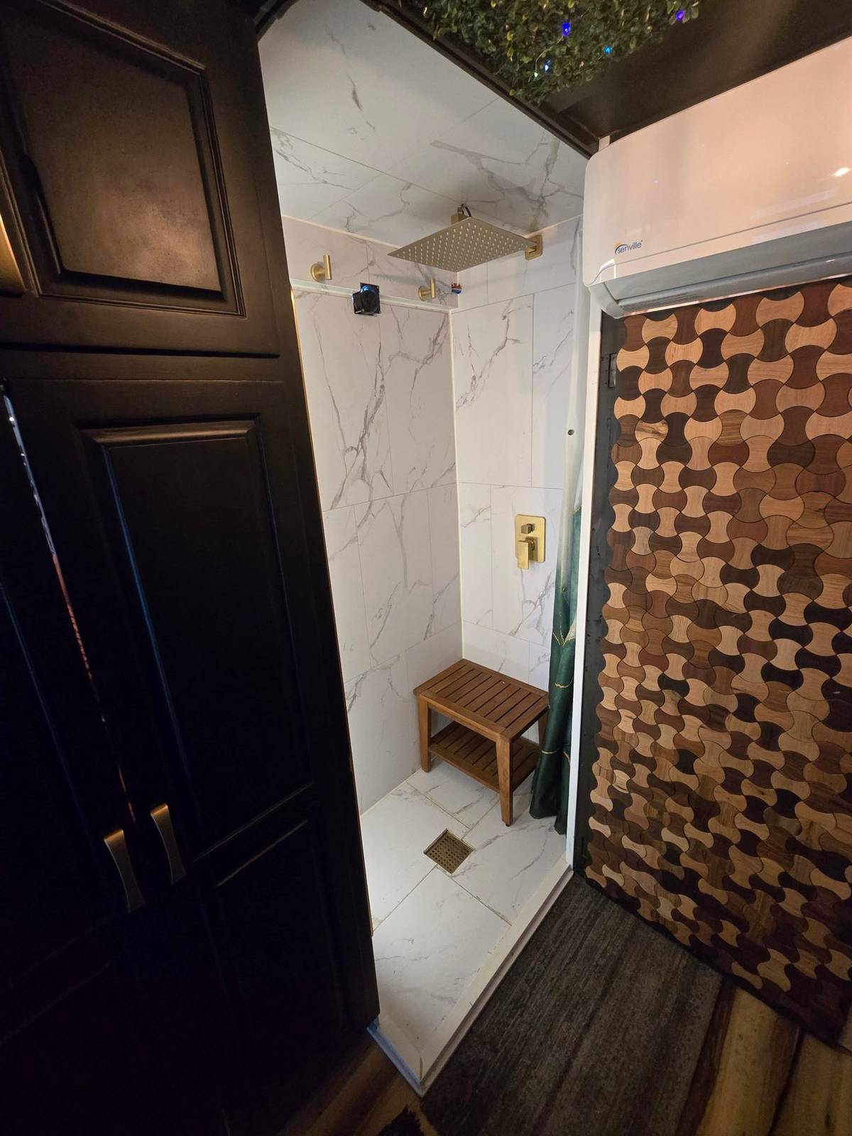 Finished custom trailer bathroom with marble-look shower and compact climate system
